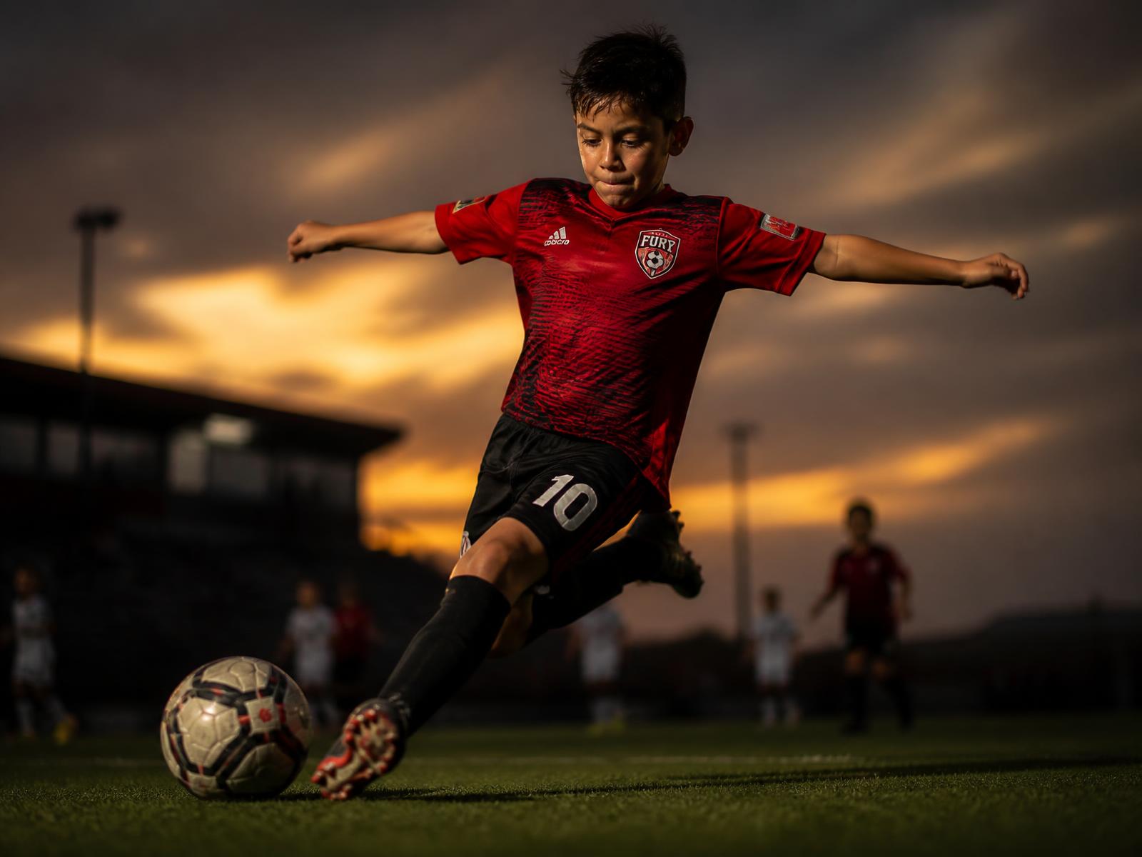 Youth athlete in uniform photographed on the field at golden hour